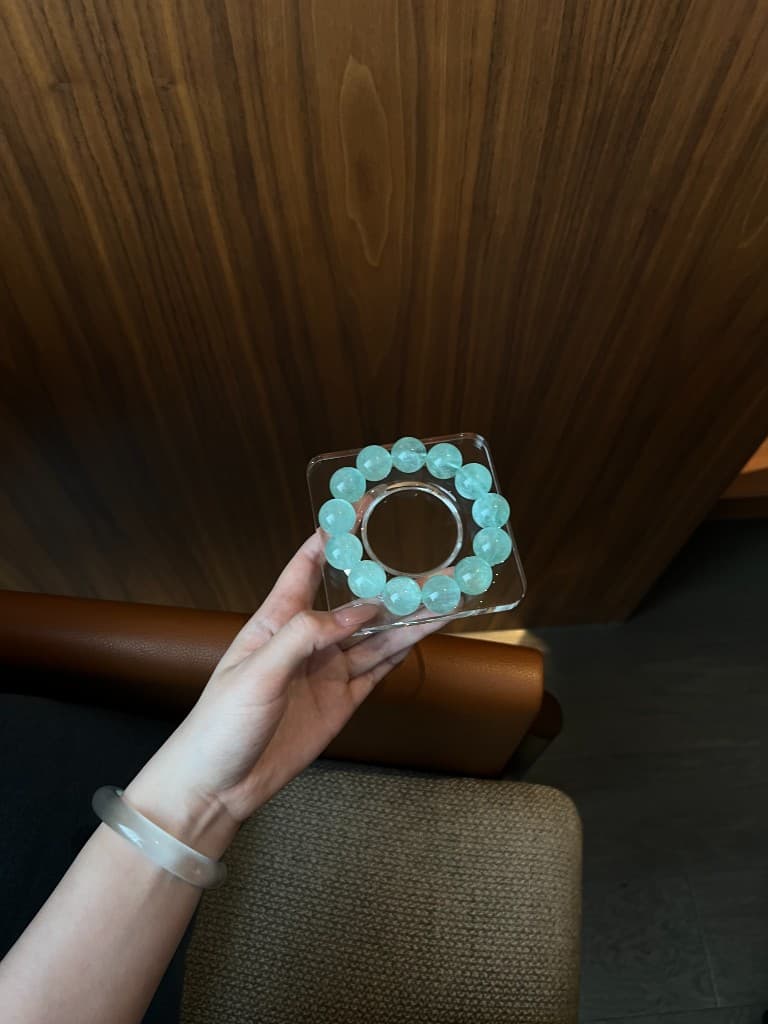 Mint quartz bracelet held against wood paneling